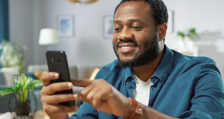 Man sitting down using a home security app on his smartphone